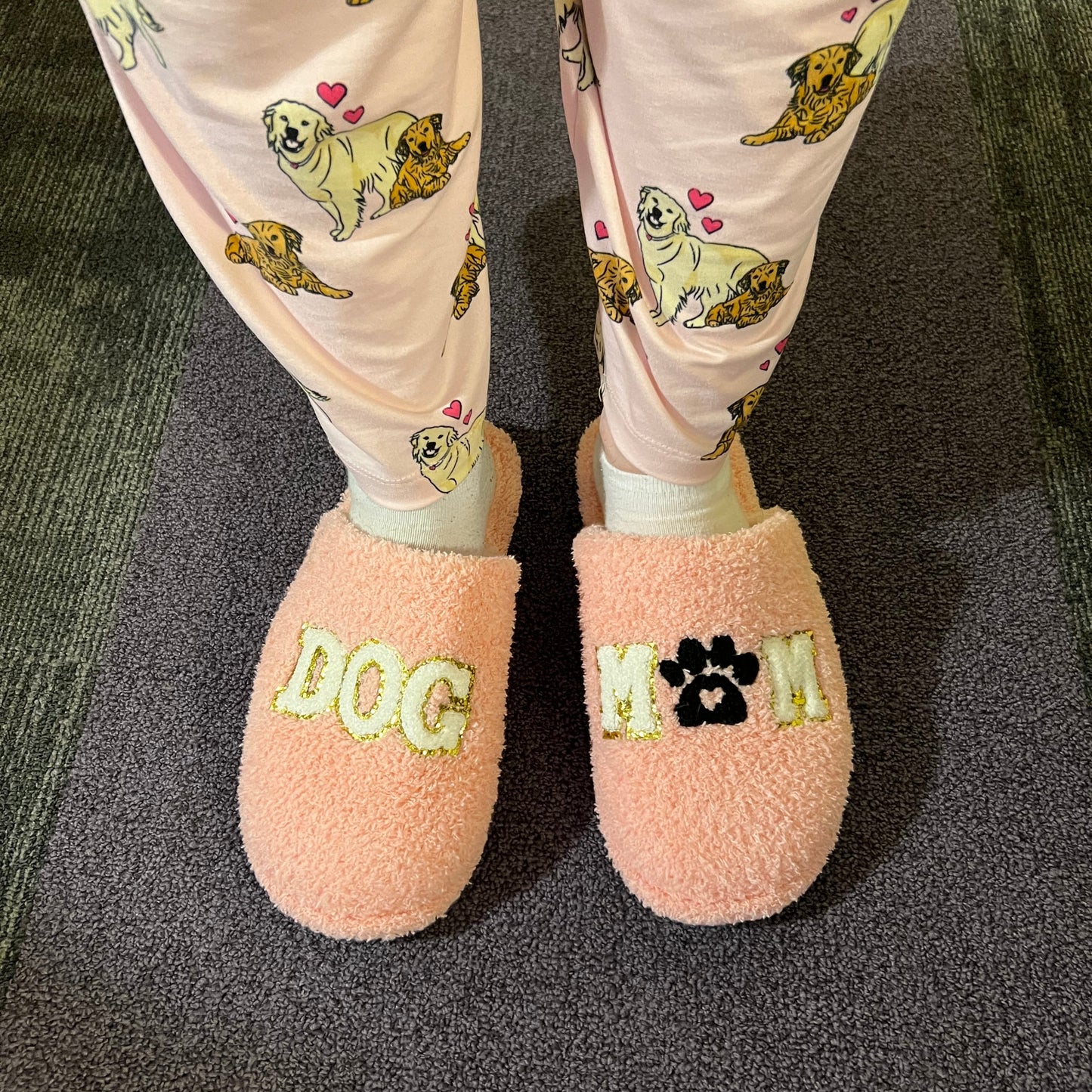 Pink slippers with 'LOVE' embroidery on a dark surface