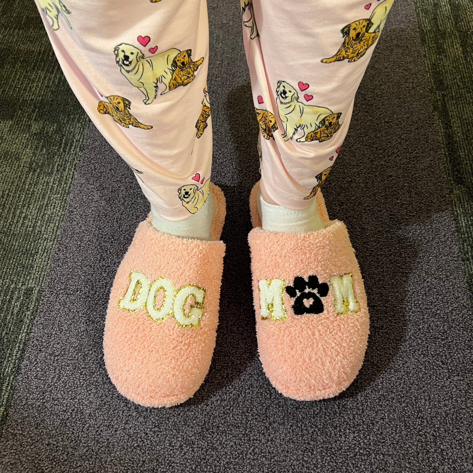 Pink slippers with 'LOVE' embroidery on a dark surface